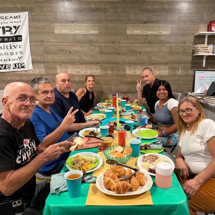 Recovery community members sharing a home-cooked dinner around one table